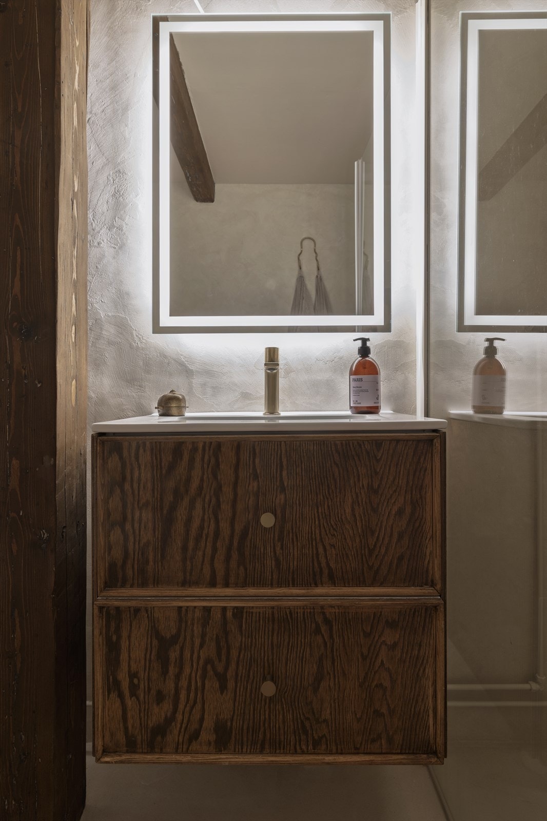 Baderomsinnredningen er spesiallaget og tilpasset av interiørarkitekt, og står i elegant harmoni med de karakteristiske trebjelkene i leiligheten. Galleribilde