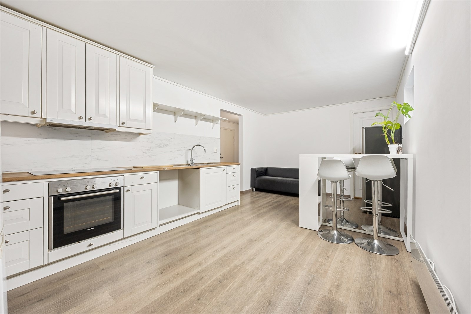 Kjøkkenet har en hvit laminatinnredning med profilerte fronter og benkeplate i heltre. Galleribilde