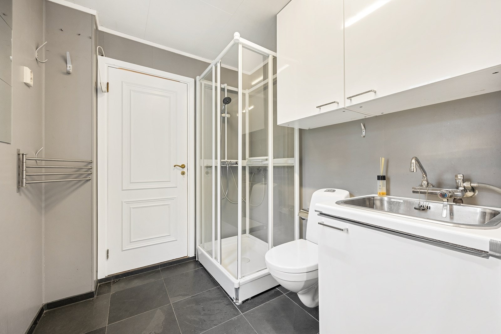 Vaskerommet er innredet med gulvstående toalett, servant, høyskap og opplegg for vaskemaskin / tørketrommel. Galleribilde