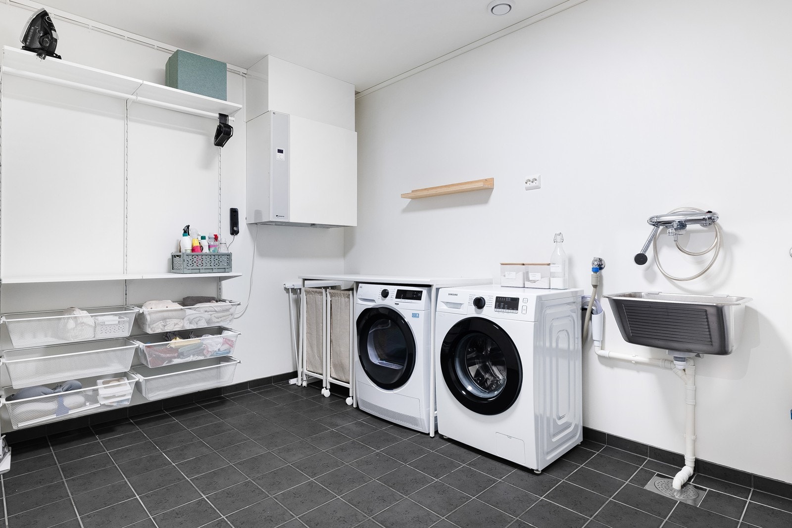 Romslig vaskerom med gulvfliser og skap for oppbevaring og lagring, utslagsvask og opplegg for vaskemaskin Galleribilde