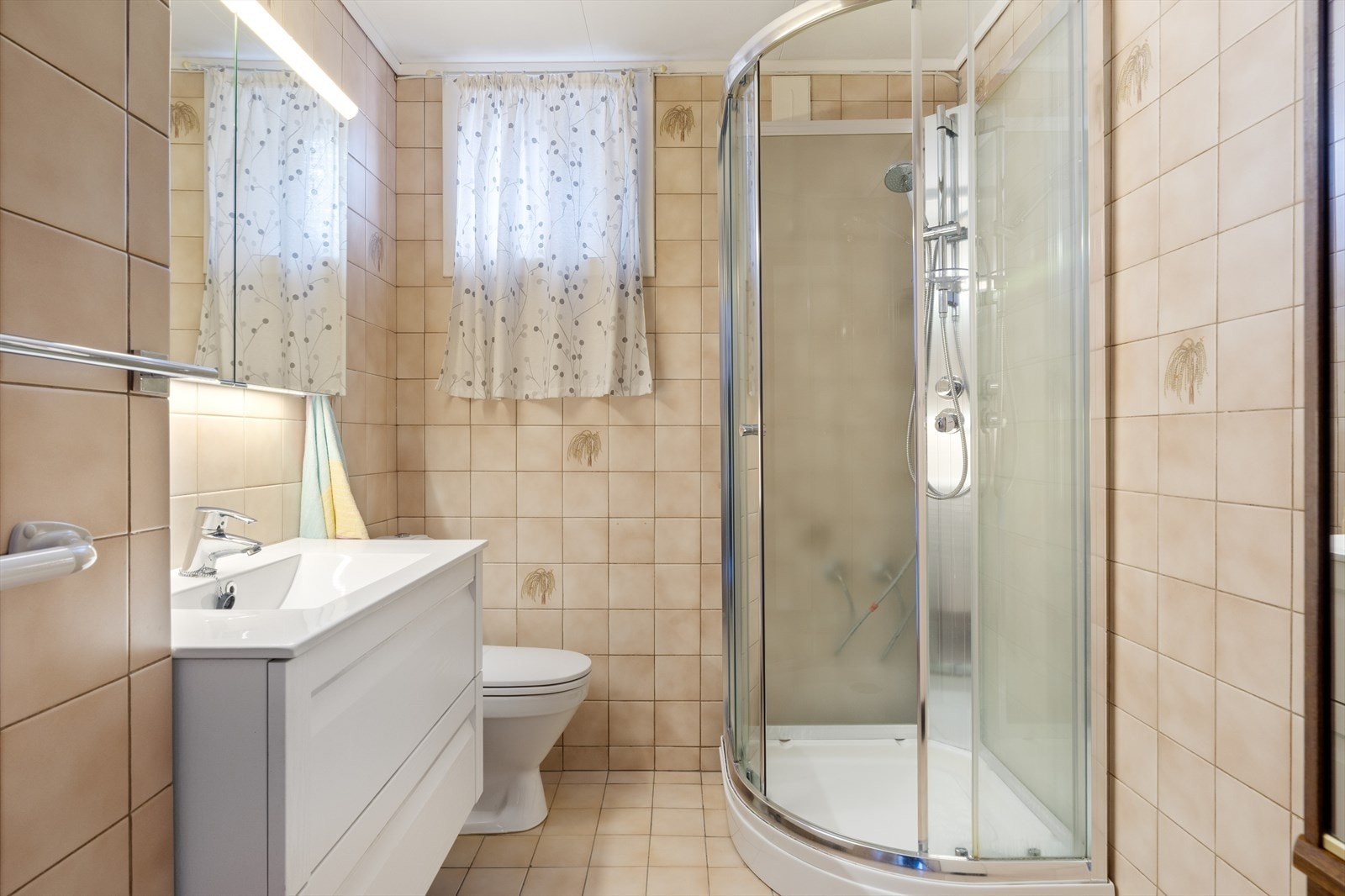 Badet er innredet med dusjkabinett, servant med møblement og wc. Galleribilde