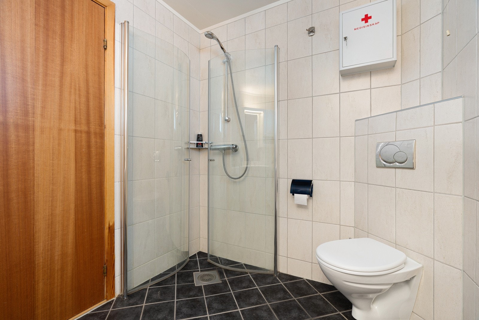 Dusjhjørne med innfellbare dusjvegger, vegghengt wc og stor innredning for lagring av baderomsartikler.