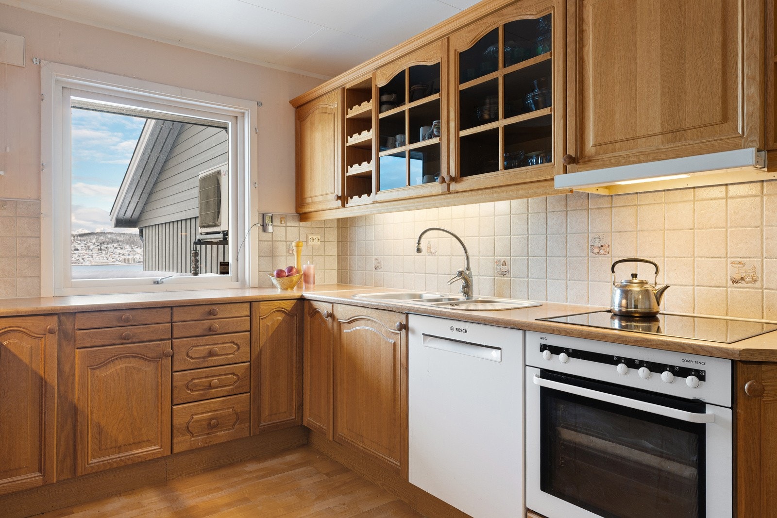 Kjøkkenet har innredning med profilerte fronter, benkeplate av laminat og flis over benkeplate.