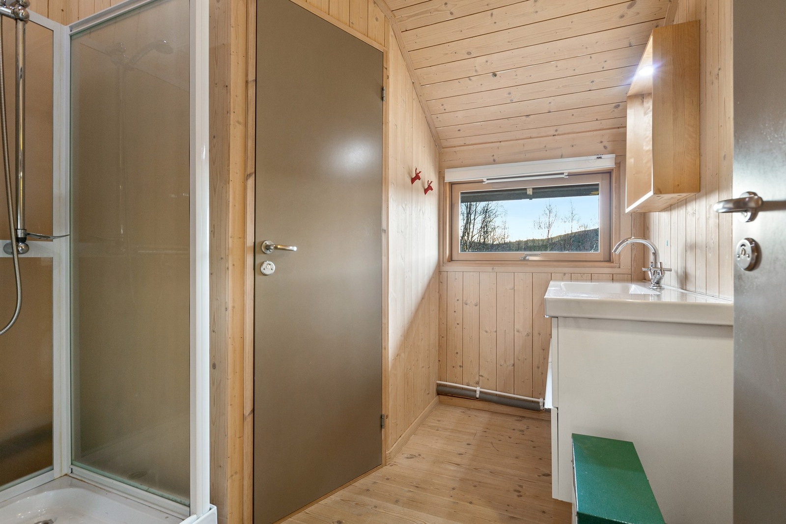 Servant med underskap og dusjkabinett, og dør inn til toalettrom med snurredo. Galleribilde