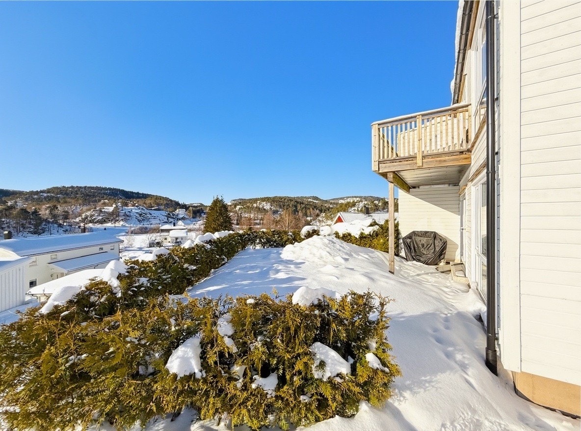 Solrik og skjermet hageflekk med hekk rundt og utsikt mot nærområdet Galleribilde