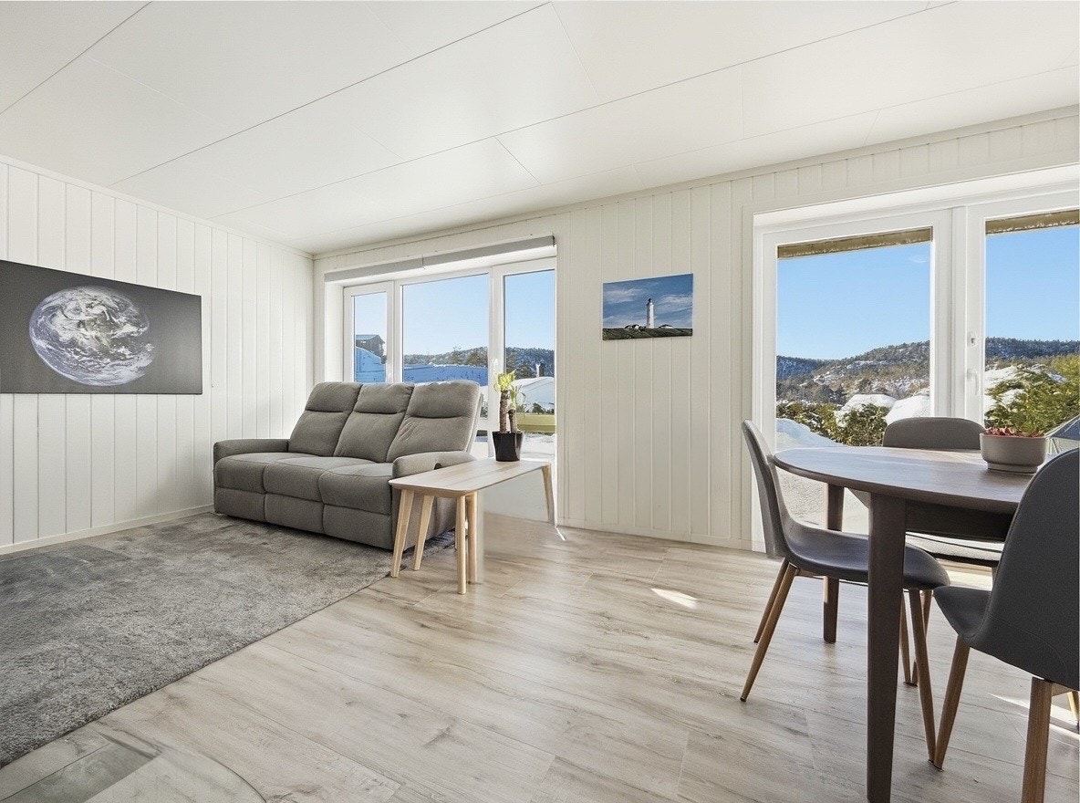 Luftig stue med spiseplass og store vinduer med flott utsikt Galleribilde