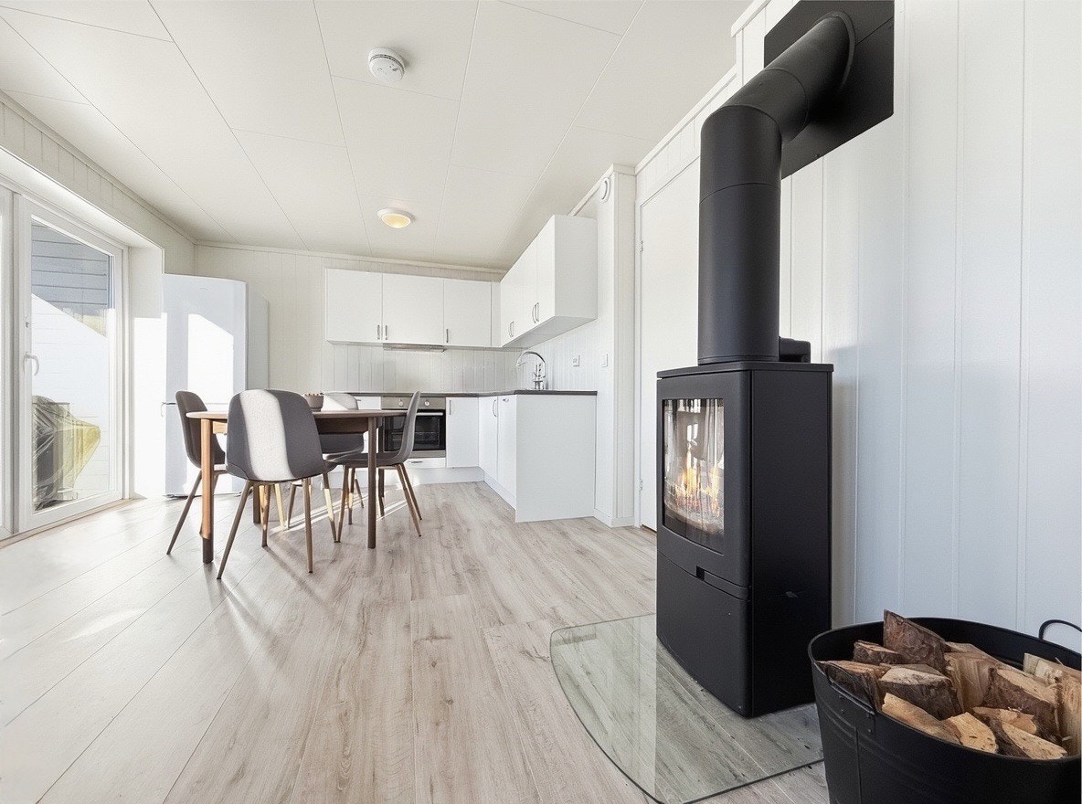 Åpen stue- og kjøkkenløsning med peisovn og utgang til terrasse Galleribilde