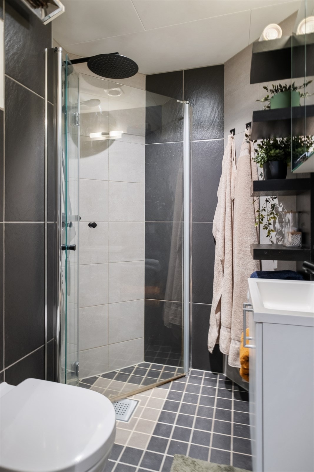 Innredningen består av et stilrent baderomsmøbel med nedfelt servant, vegghengt toalett som gir et luftig inntrykk, samt et praktisk dusjhjørne med dusjvegger som utnytter plassen godt. Galleribilde