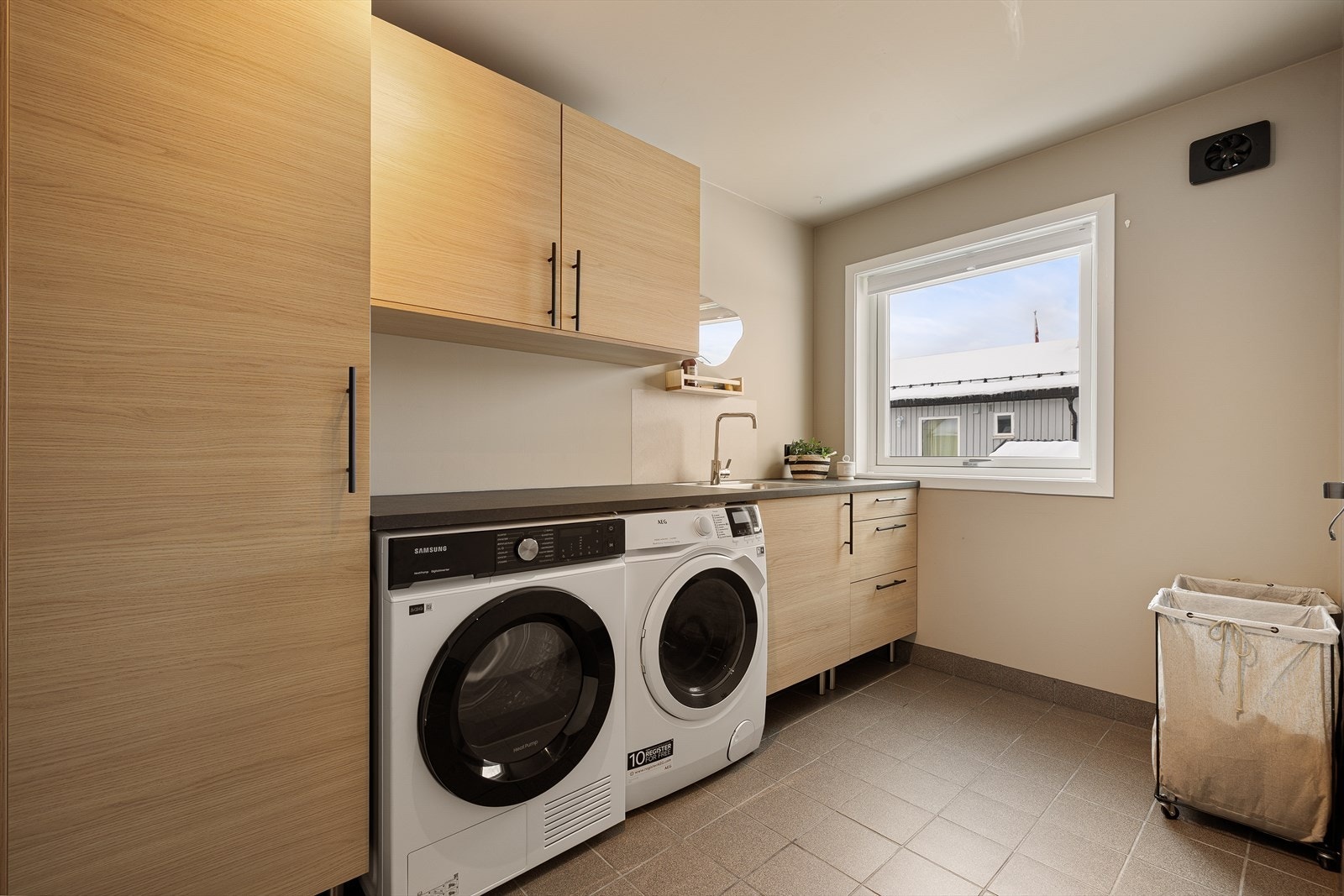 Praktisk vaskerom med god benkeplass og rikelig med lagringsplass i skap og skuffer. Galleribilde