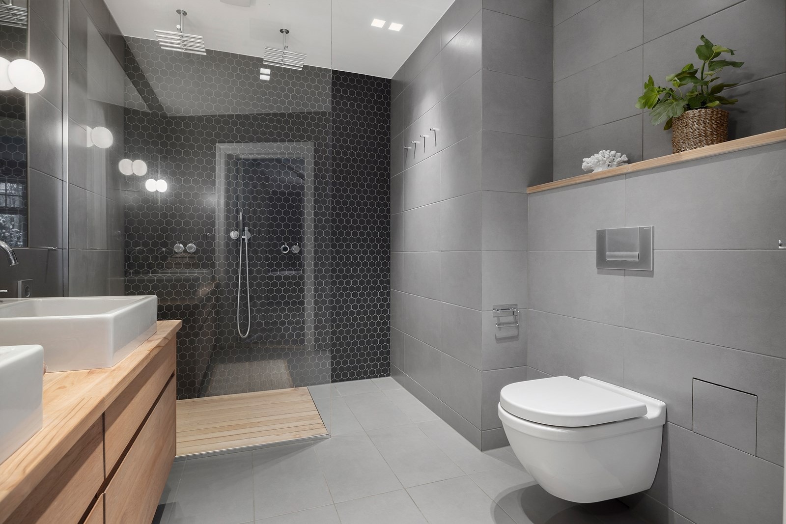 Innredningen består av dobbel servant med underskap, speil med belysning, vegghengt toalett og dusj med herdet glassvegger. Mekanisk avtrekk. Galleribilde