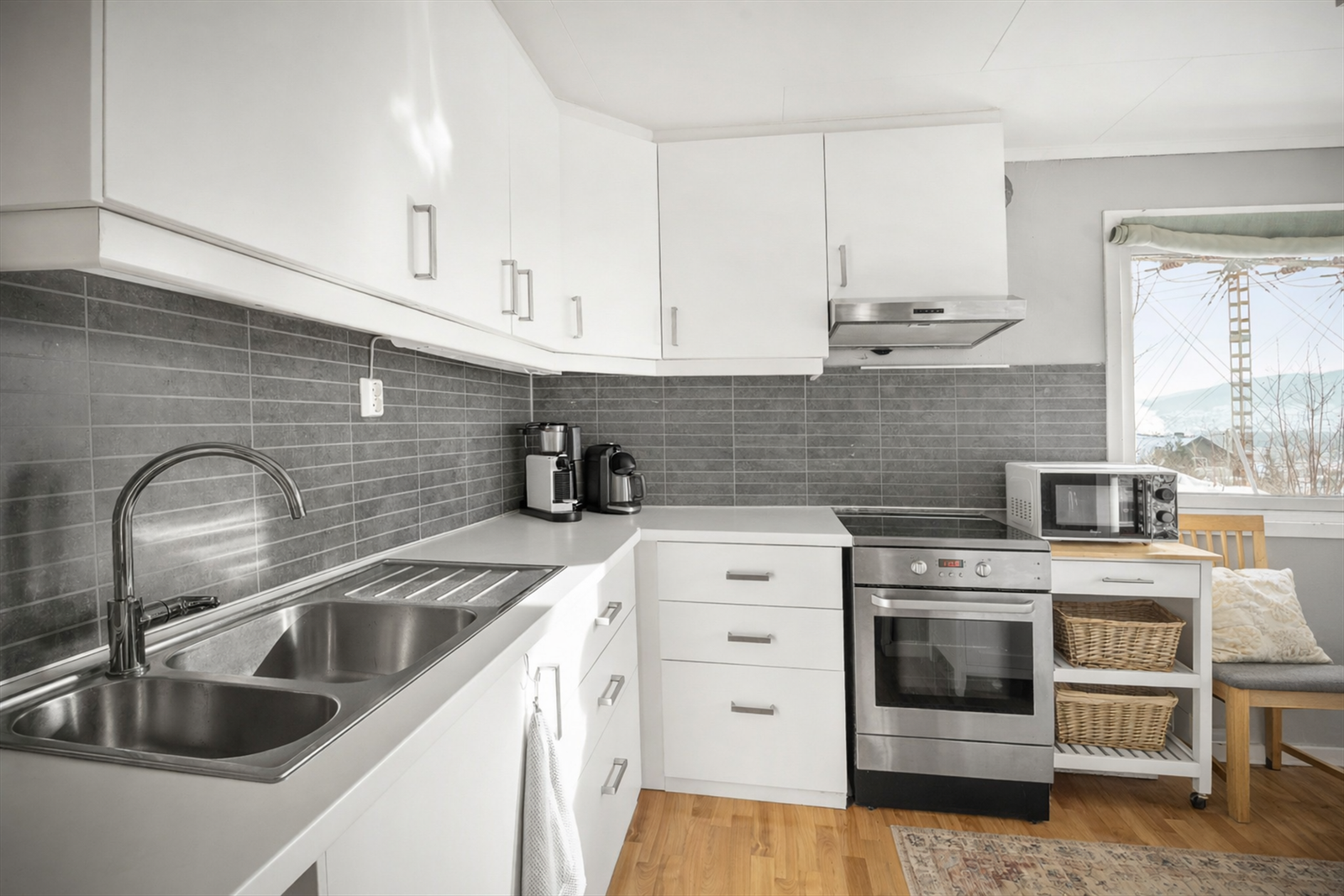 Kjøkkenet i utleiedelen har en hvit, glatt innredning med laminert benkeplate. (Bildet/løst interiør er digitalt ordnet). Galleribilde