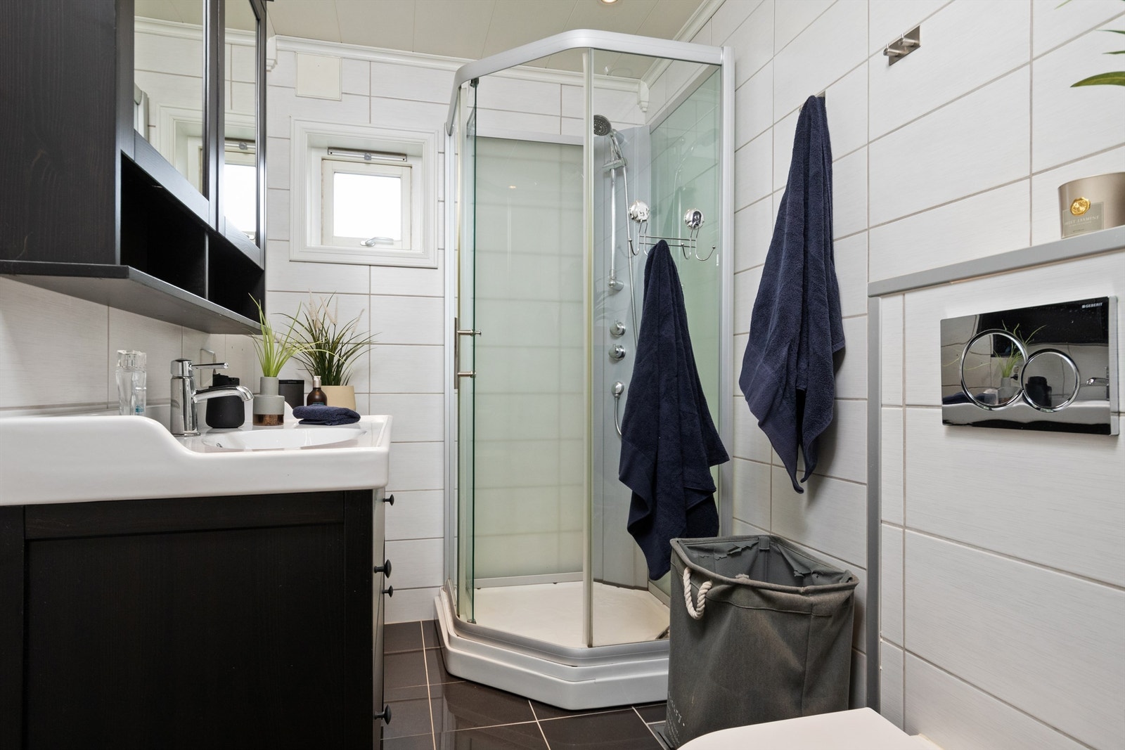 Badet har flislagt gulv med varmekabler, flislagte vegger og malt panel i tak, og er innredet med servantinnredning, dusjkabinett og wc Galleribilde