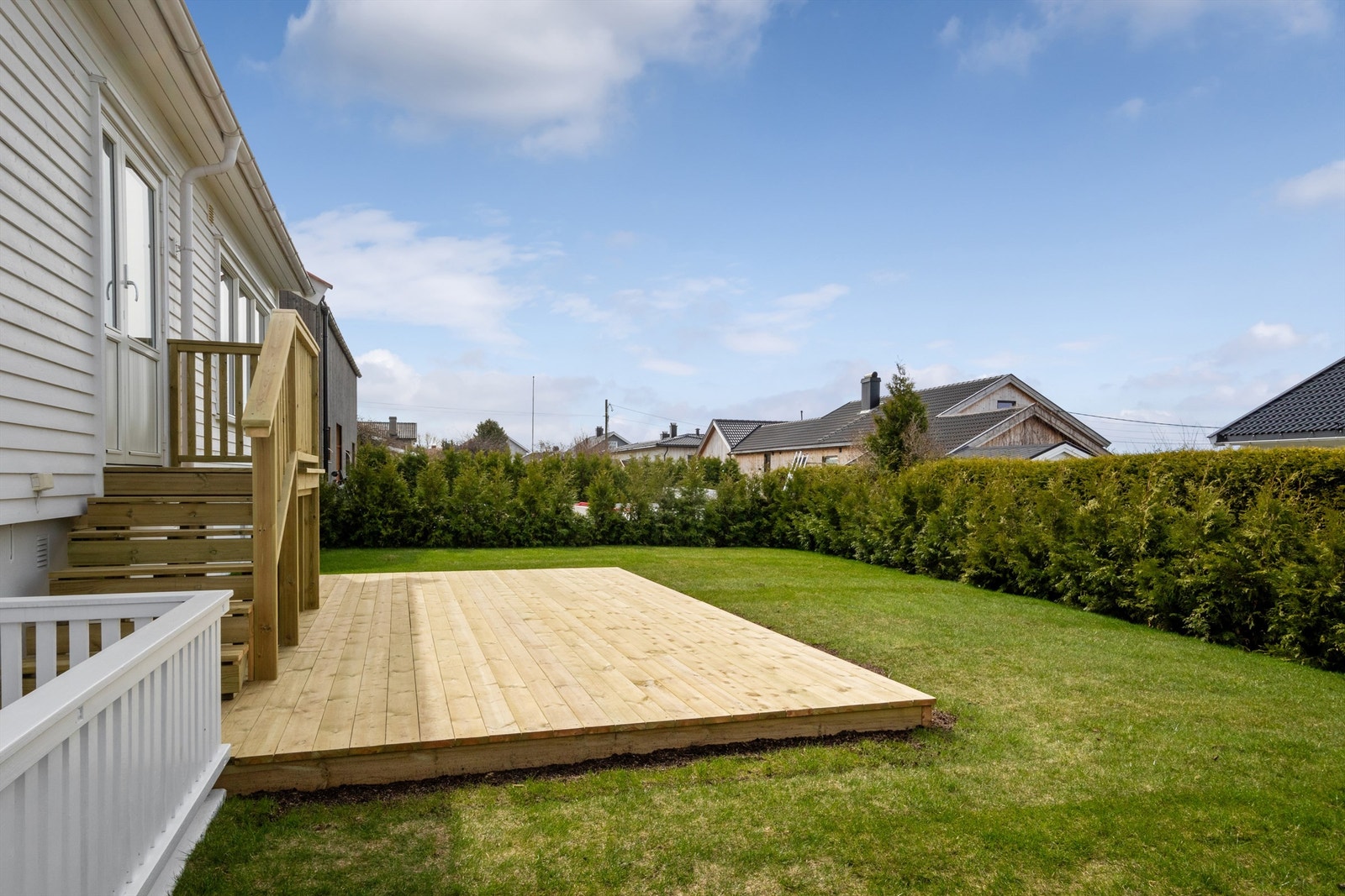 Tomten er pent opparbeidet med plen, hekk og en solrik terrasseplatting. Galleribilde