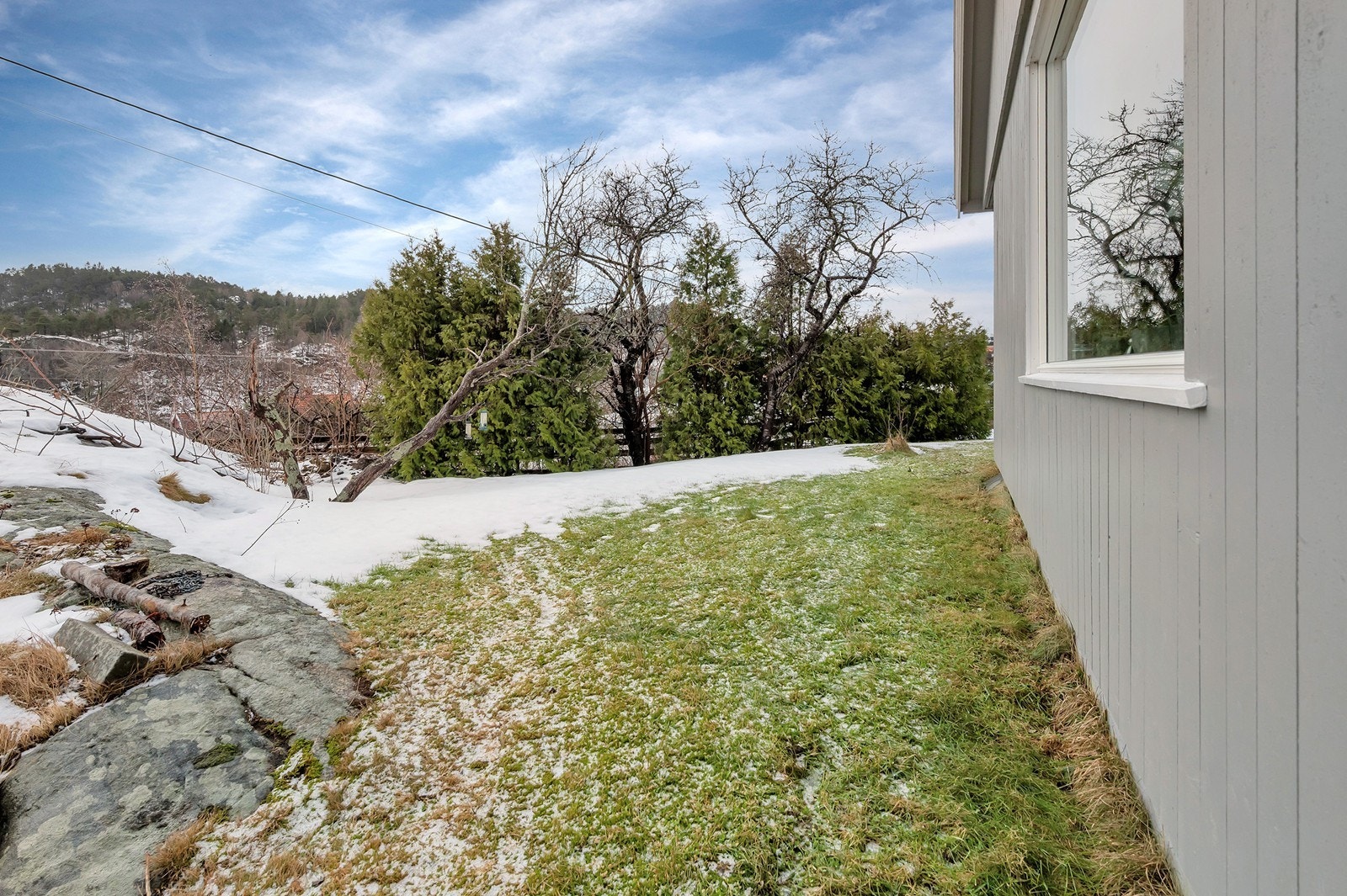 Utsiden av vinduet hvor tomten er opparbeidet med gressplen rundt. Galleribilde