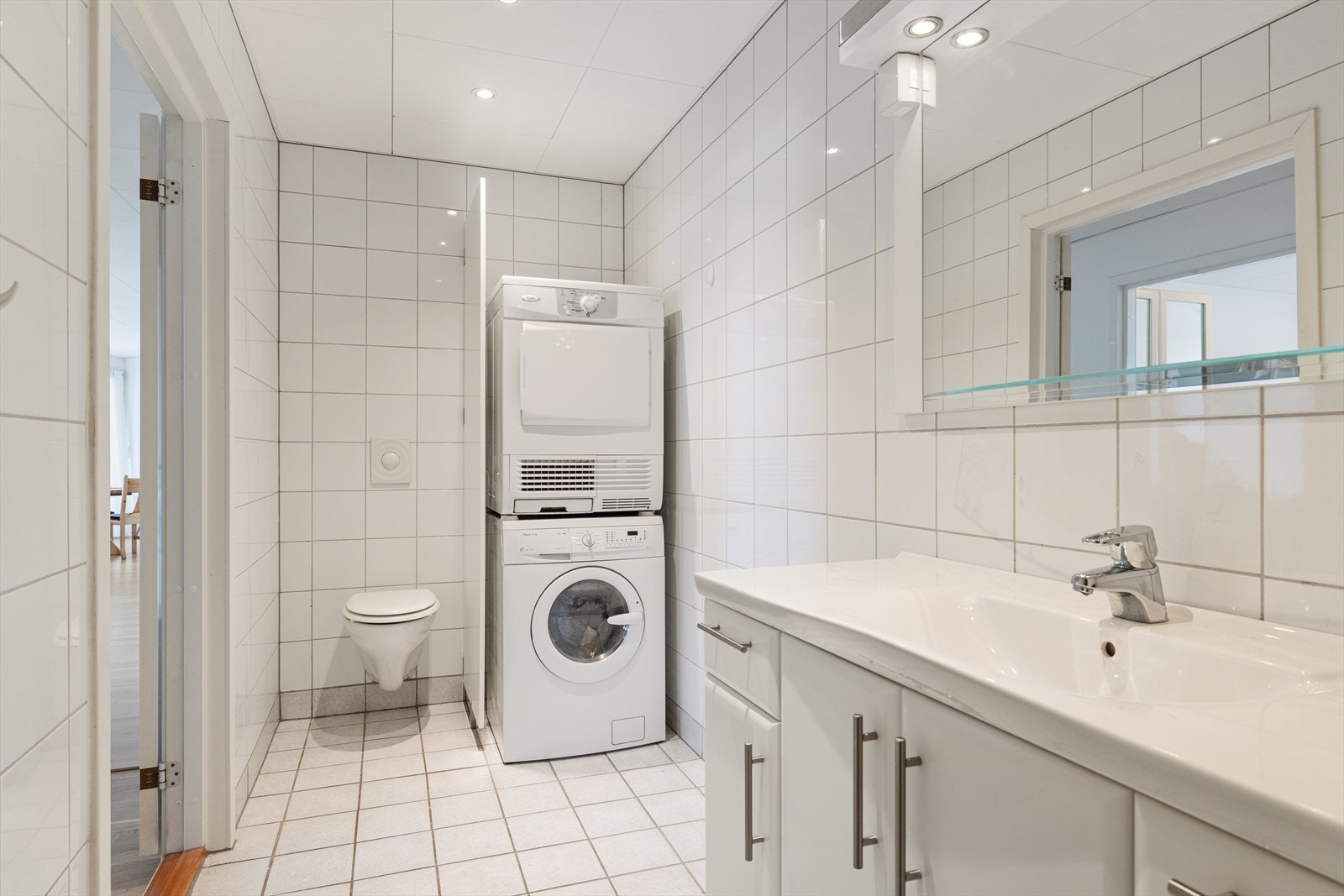 Moderne innredning med heldekkende servant, speil med lys og vegghengt toalett. Galleribilde