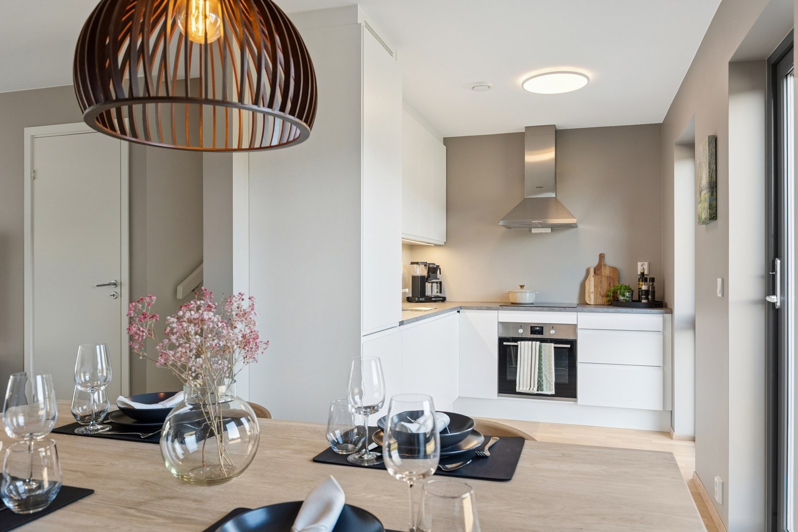 Et plassbesparende og moderne kjøkken med effektiv L-utforming og åpen løsning mot spiseplass - en sosial og praktisk løsning i hverdagen. Galleribilde