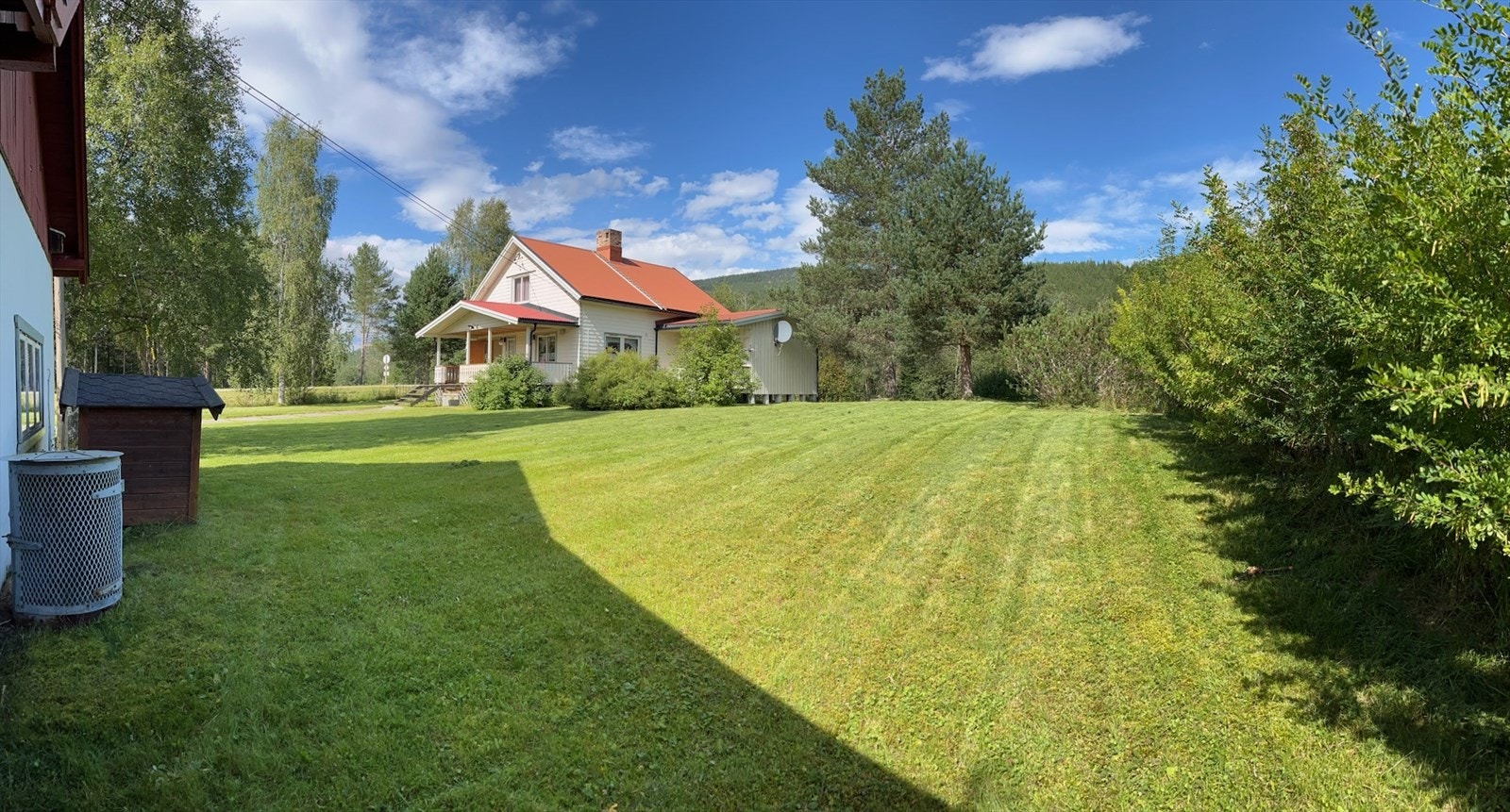 Stor og flat tomt som er pent opparbeidet med plen og beplantning. Galleribilde