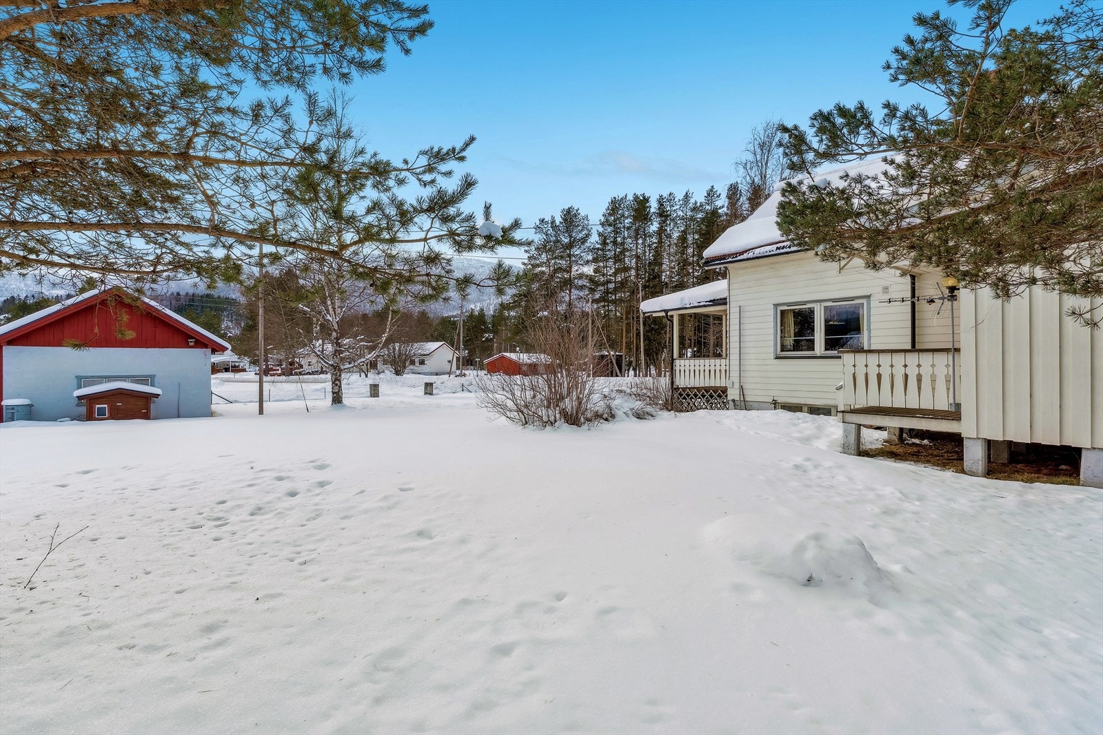 Utsyn fra baksiden av huset mot garasjen og nærområdet. Galleribilde