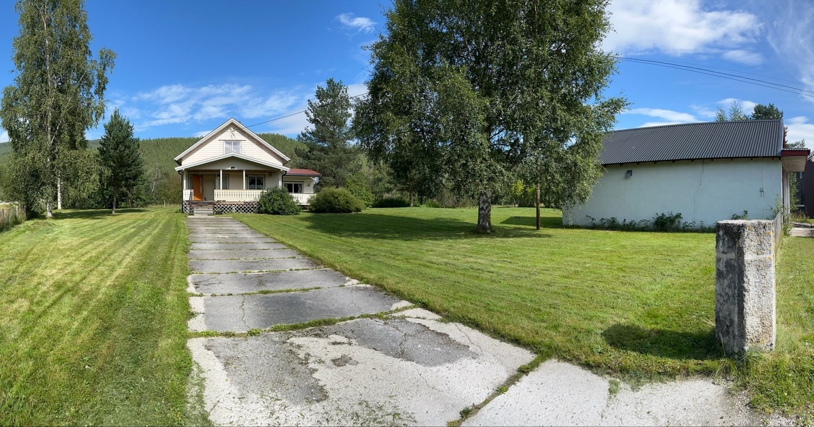 Enebolig fra 1953 med en stor, frittstående garasjebygning på en flat tomt med plen. Galleribilde