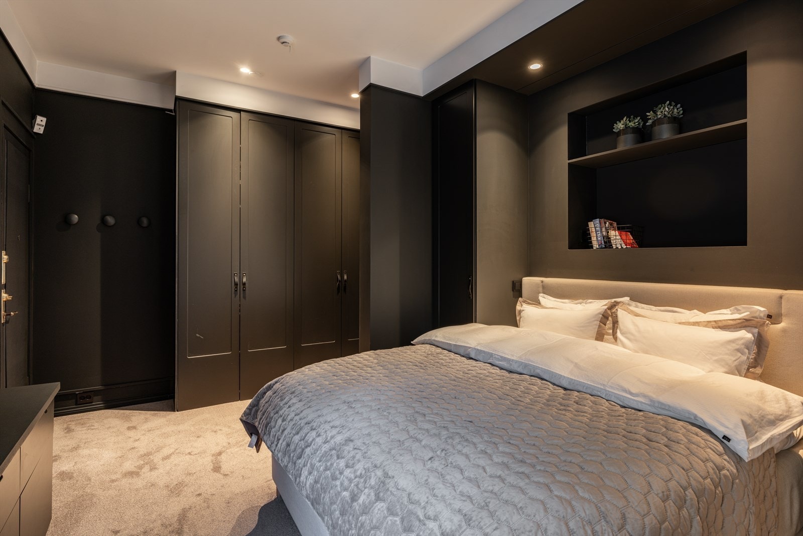 Rommet har gjennomførte, plassbygde garderobeløsninger som også er integrert rundt dobbeltsengen, samt en nisjeløsning i vegg. Under vinduet er det etablert en plassbygget sjenk som både er praktisk og estetisk tiltalende. Galleribilde