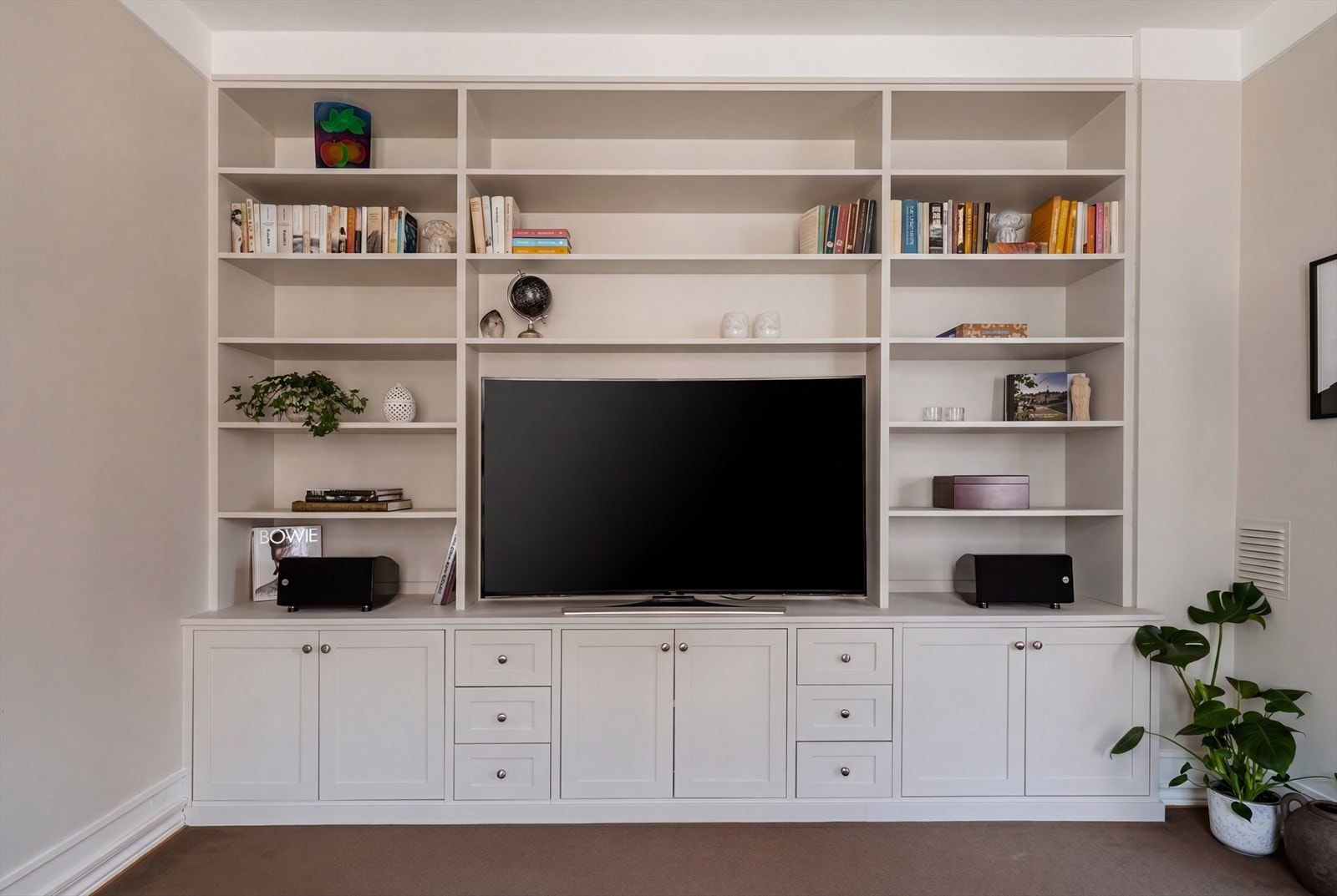 Rommet kompletteres av en smakfull, plassbygget reolløsning med integrert og diskret TV-møblement. Galleribilde