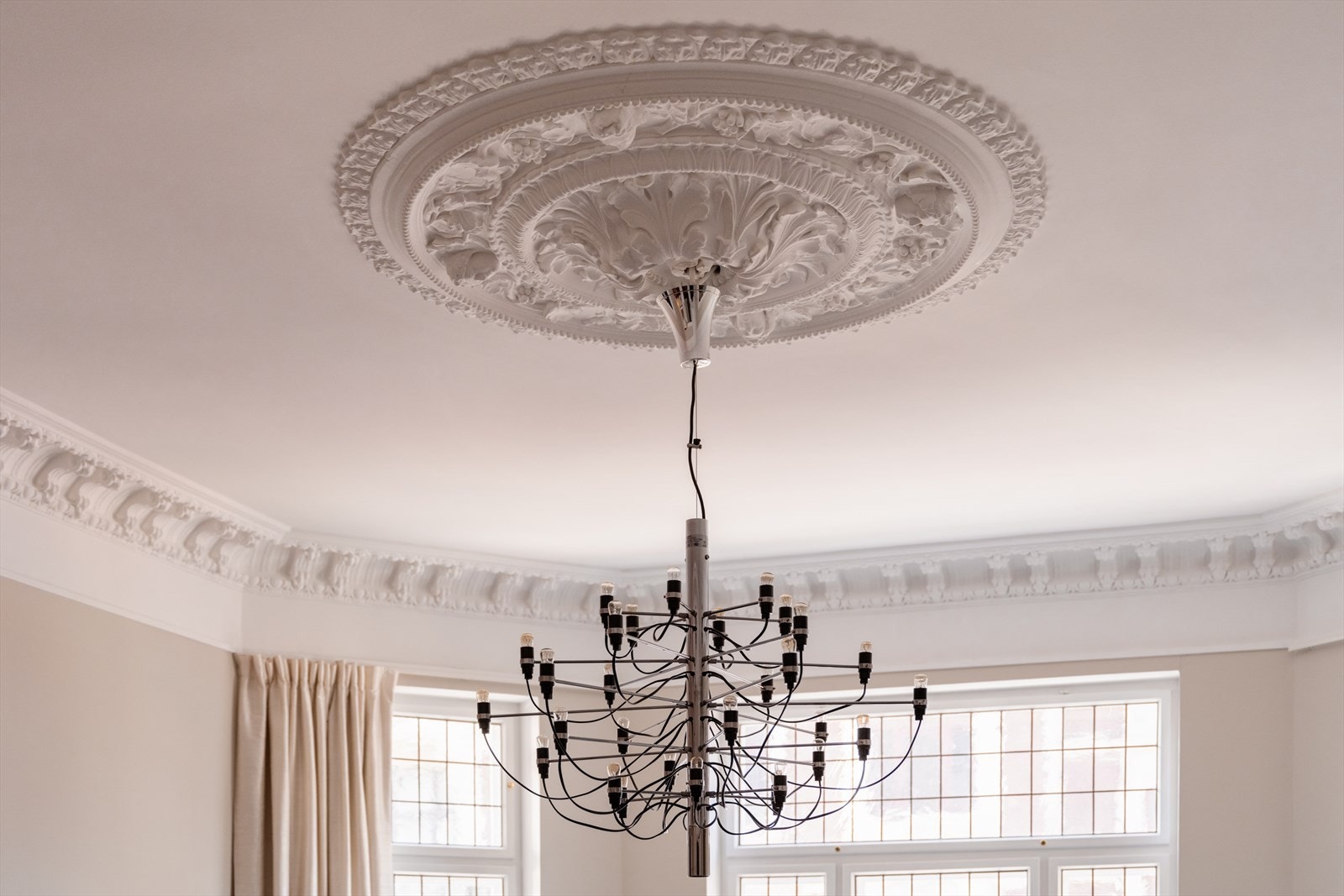 Originale detaljer som stukkatur og rosetter i taket understreker leilighetens historiske sjarm. Galleribilde