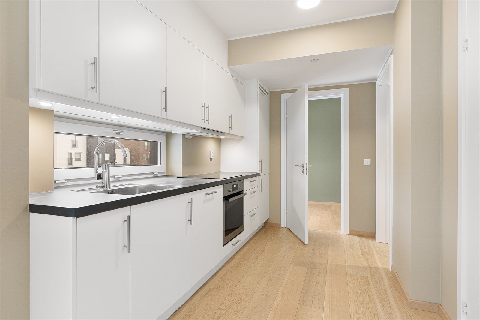 Kjøkkeninnredningen har hvite, glatte fronter og laminert benkeplate. Galleribilde