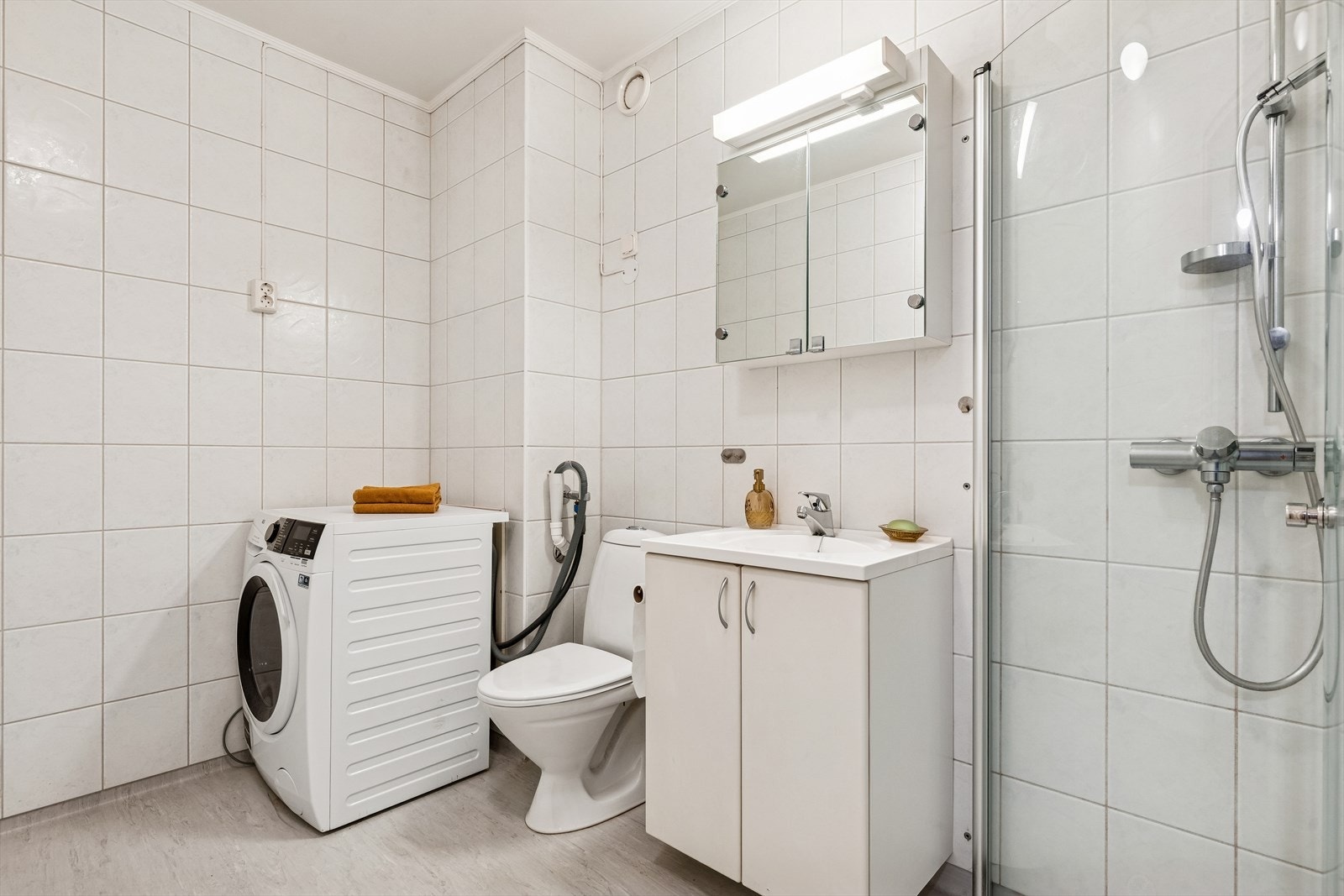 Badet er funksjonelt innredet med dusjhjørne, toalett og opplegg for vaskemaskin. Galleribilde