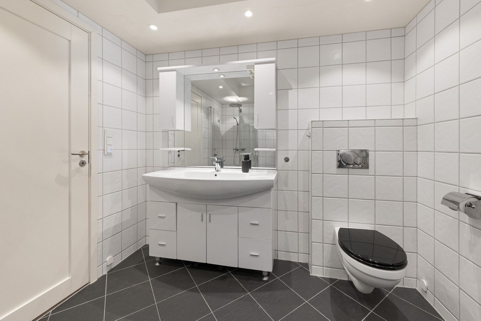 Hvit glatt innredning med kombinasjon av skuffer og skap. Heldekkende hvit vask. Galleribilde