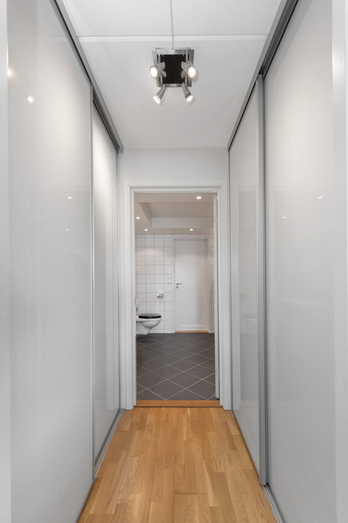 Praktisk garderoberom med skyvedørsskap mellom bad og soverom Galleribilde