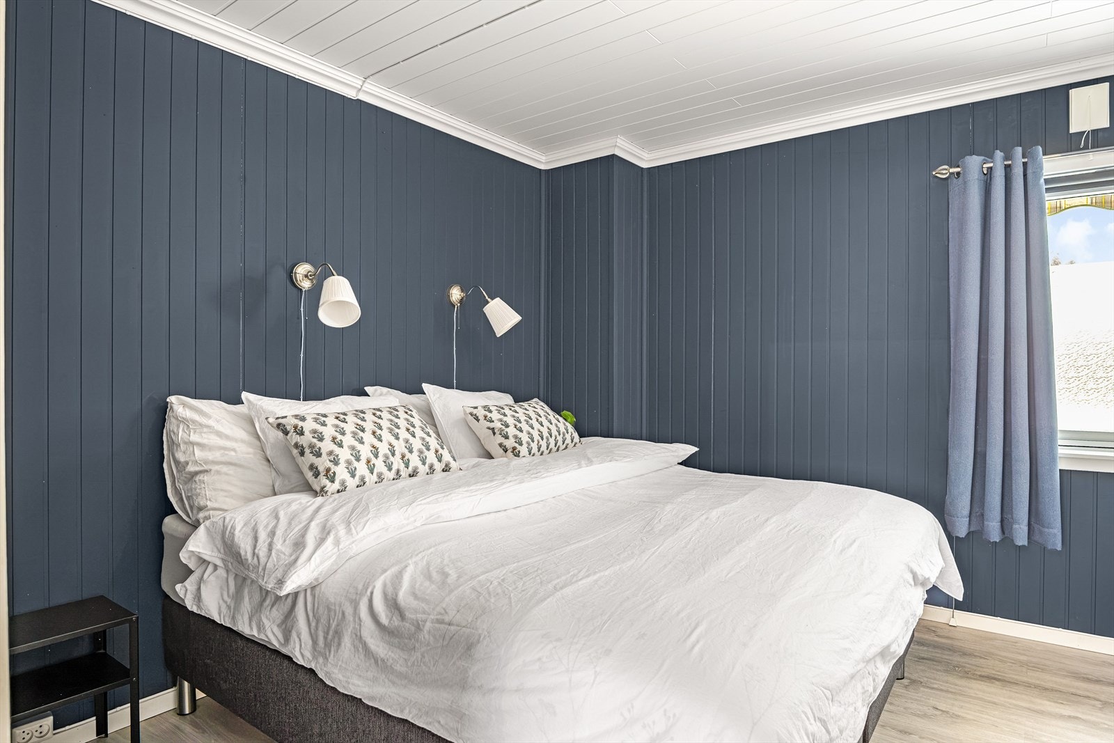 Romslig soverom med panelte vegger og tak, og laminatgulv. Galleribilde