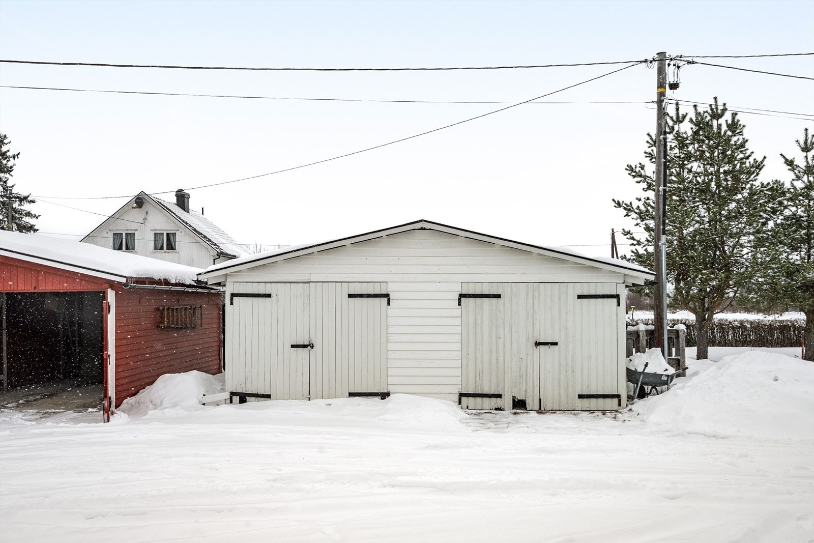 Garasjen har sidehengslede, stedsbygde porter av tre og tak tekket med metallplater. Galleribilde