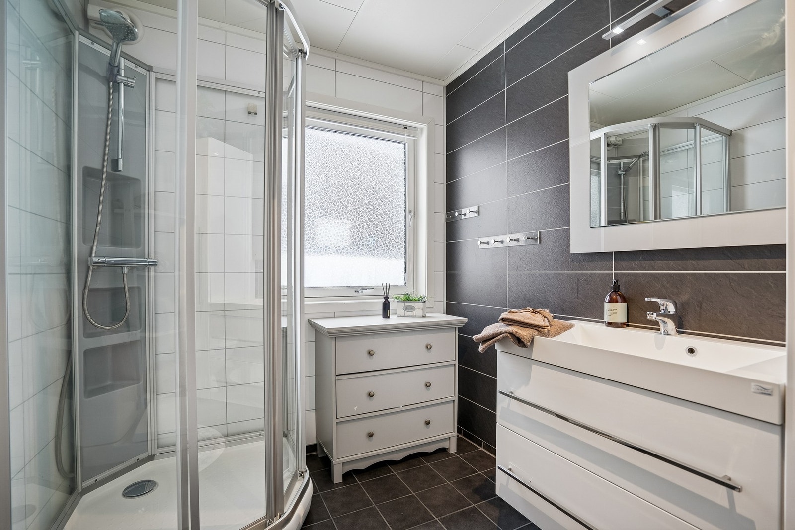 Rommet er innredet med dusjkabinett, toalett, vask, lys baderomsinnredning og opplegg for vaskemaskin. Galleribilde