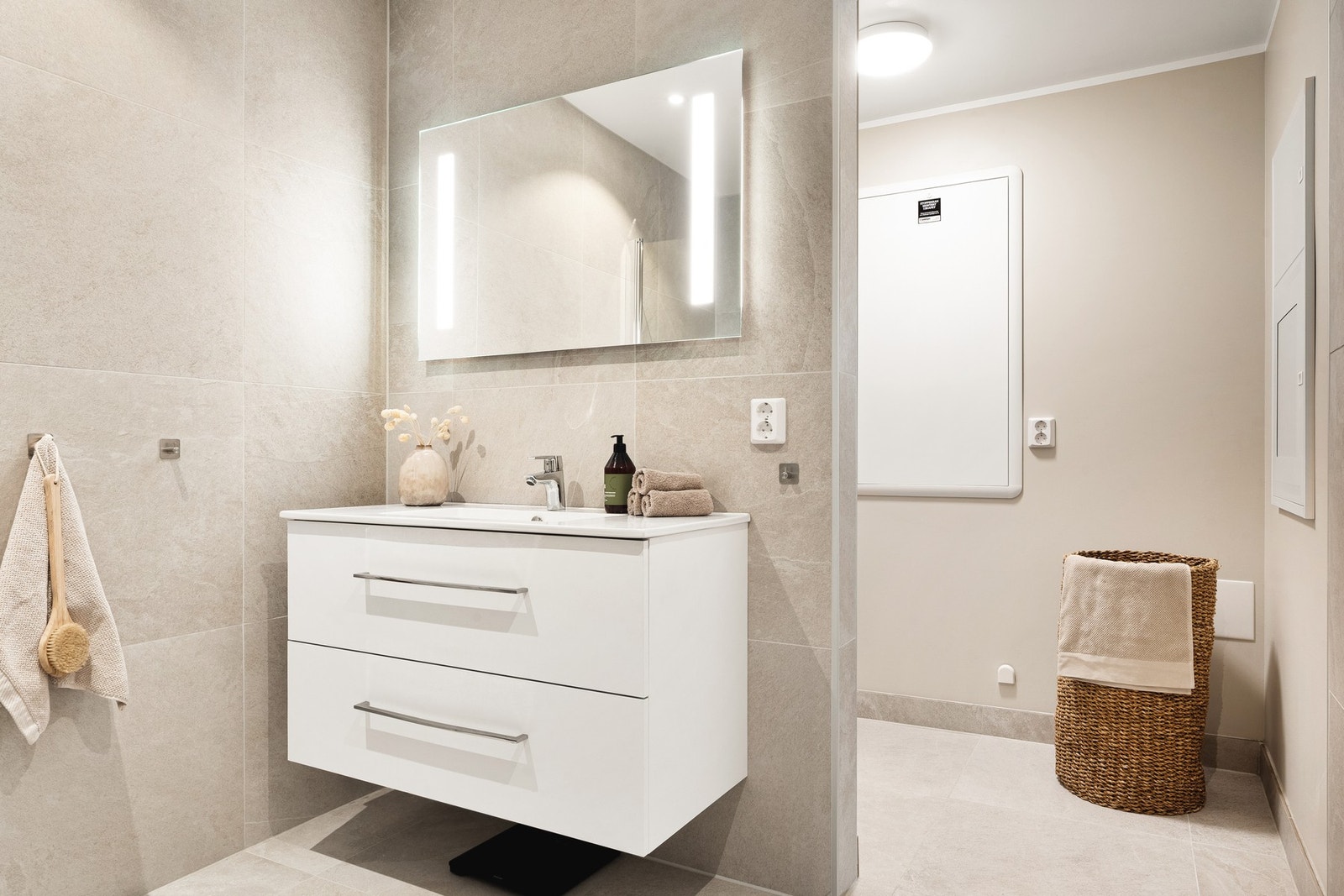 Badet er innredet med vegghengt toalett, servant med innredning, dusjghjørne og opplegg for vaskemaskin. Galleribilde