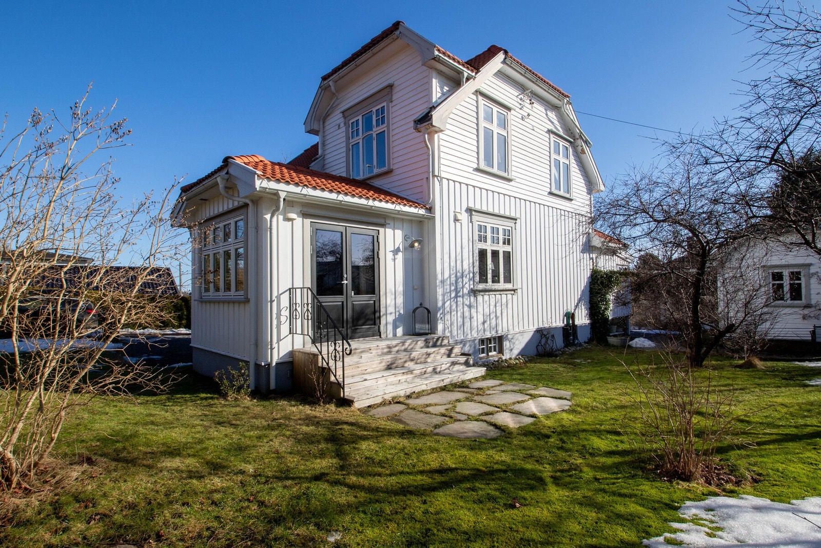 Den romslige tomten på 728,9 kvm er lett skrånende og pent opparbeidet med store plenarealer, frodig beplantning og skiferlagte partier som skaper et variert og innbydende uterom. Galleribilde