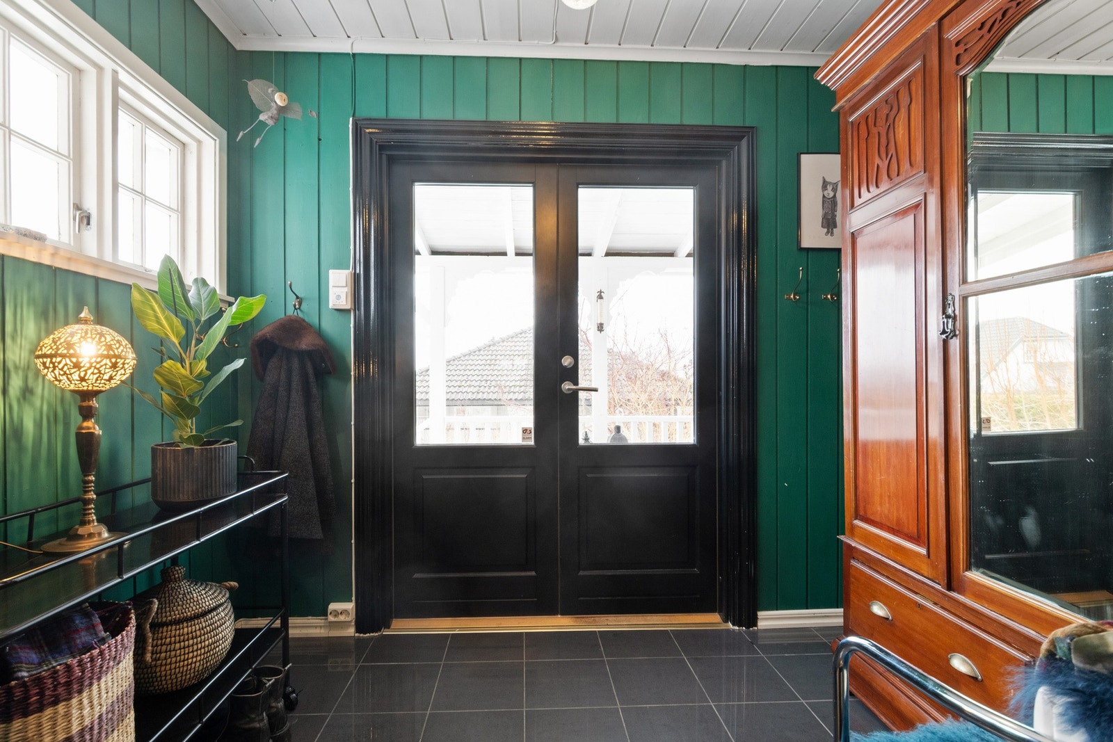 Entréen har grønnmalt panel på veggene og koksgrå fliser på gulv med gulvvarme. Galleribilde