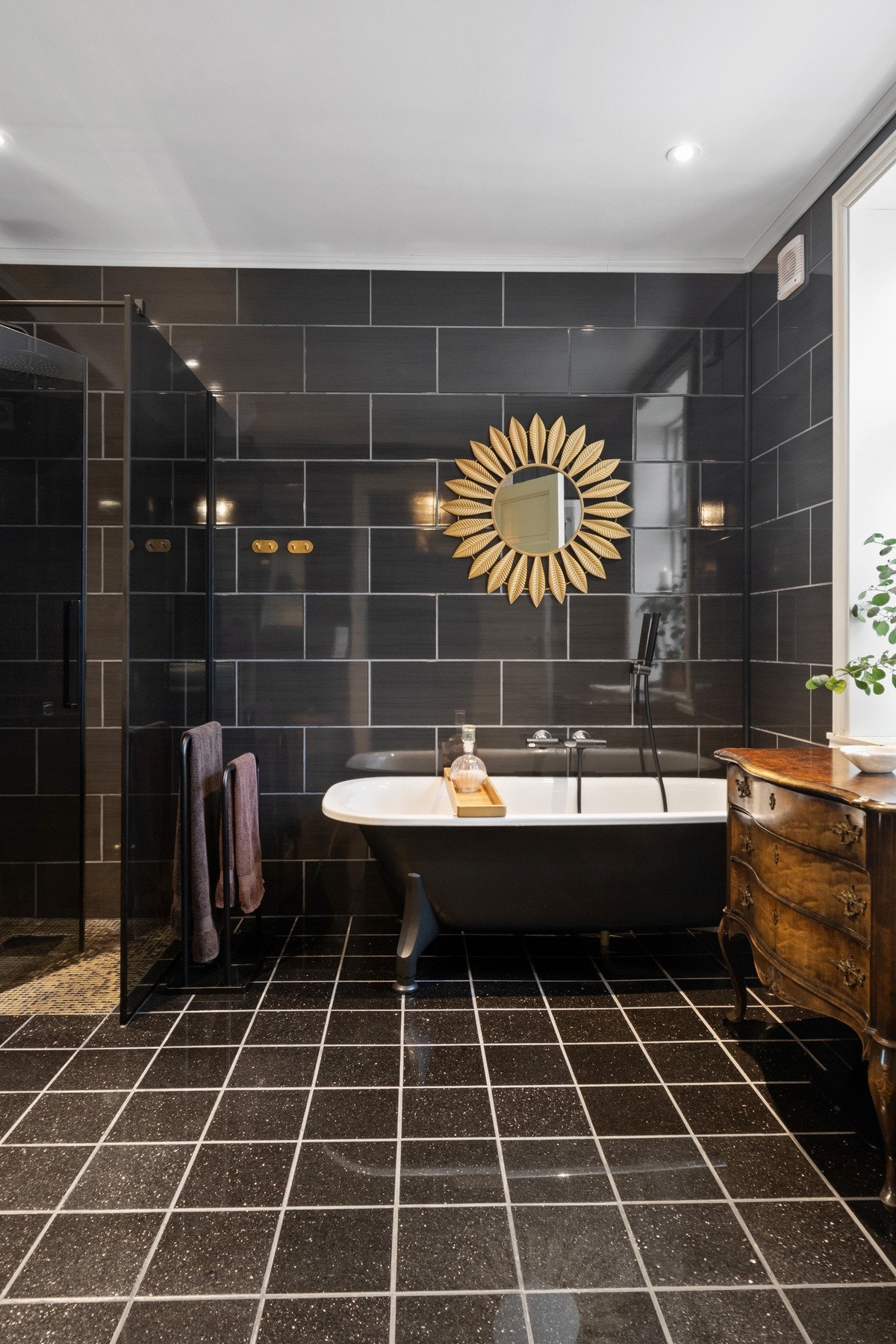 Videre er badet utstyrt med vegghengt toalett, badekar og dusjhjørne med regnfalldusj og sotede glassvegger. Galleribilde