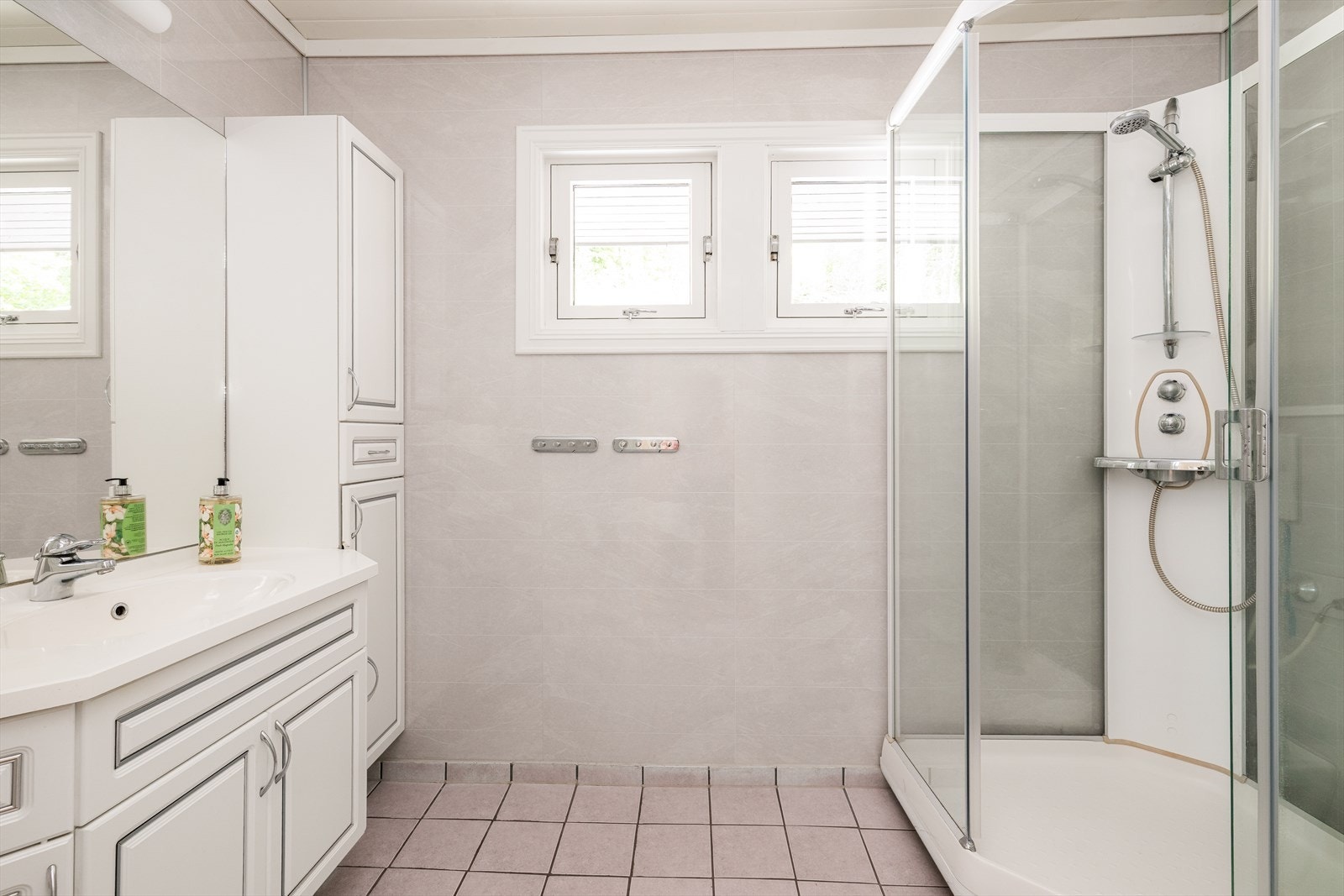 Badet har flis med underliggende smøremembran på gulv, og baderomsplater på vegger. I taket er det etablert smartpanel. Det er ikke noe dokumentasjon på utførelse. Rommet er innredet med vegghengt servantskap, dusjkabinett og vegghengt toalett. Galleribilde