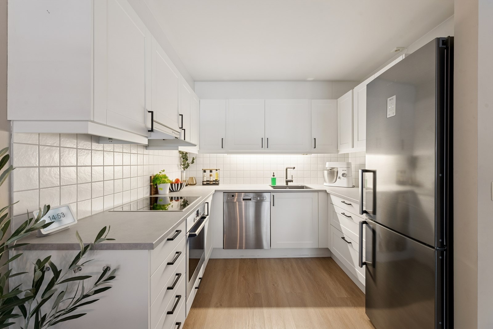 Kjøkkeninnredningen er U-formet og har godt med skap- og benkeplass. Fliser mellom benk og overskap. Galleribilde