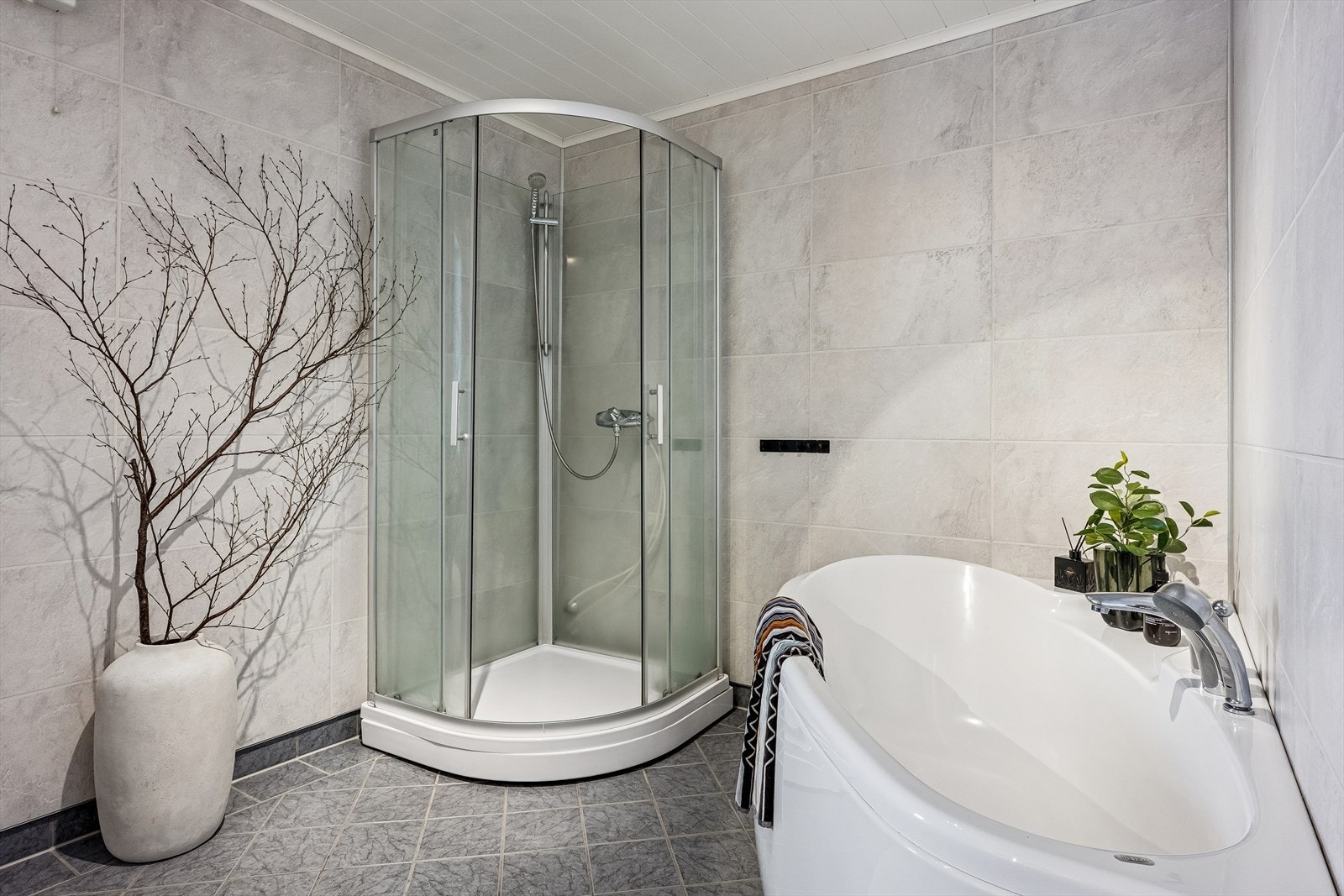 Rommet er utstyrt med dusjkabinett, badekar, vegghengt toalett, og innredning. Galleribilde