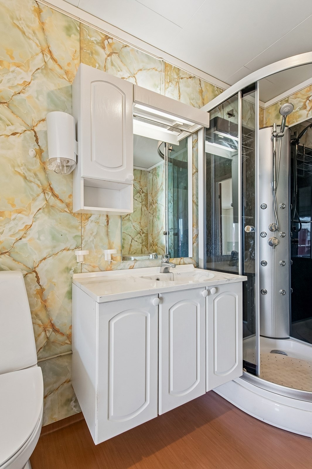 Badet er innredet med servantmøbel med speil og belysning, toalett og dusjkabinett. Galleribilde