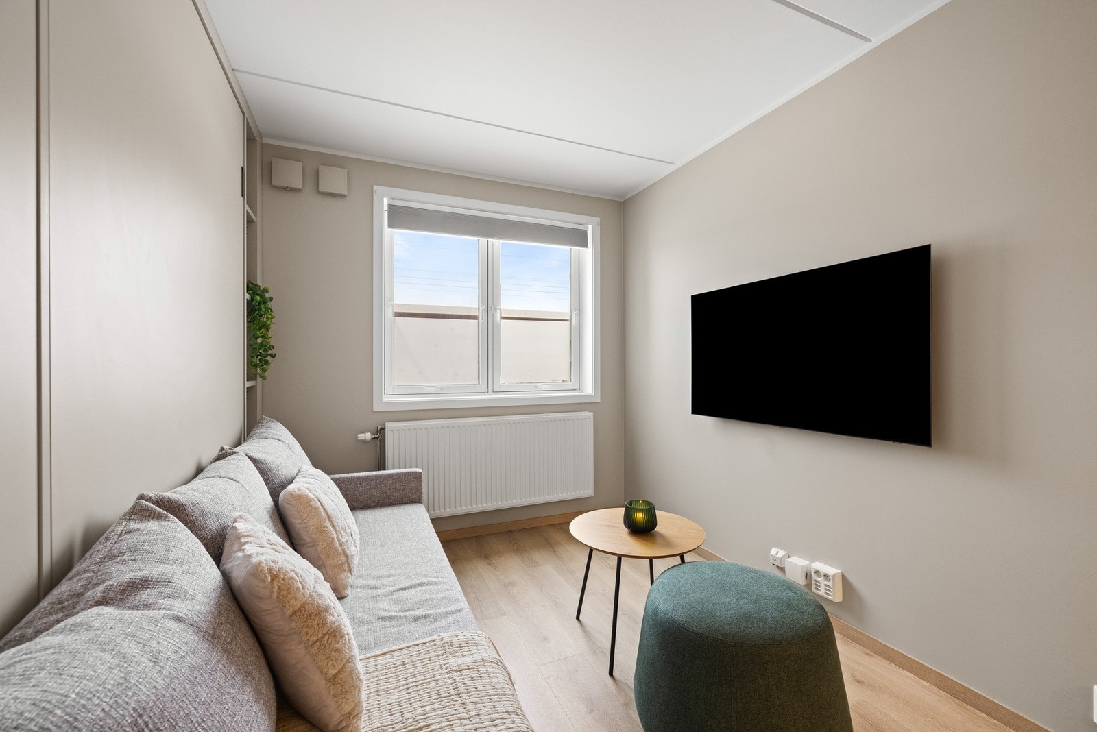 Leiligheten har en smart og plassbesparende løsning med spesialtilpasset skapseng integrert i stueinnredningen, kombinert med sofa og garderobeløsning. Galleribilde