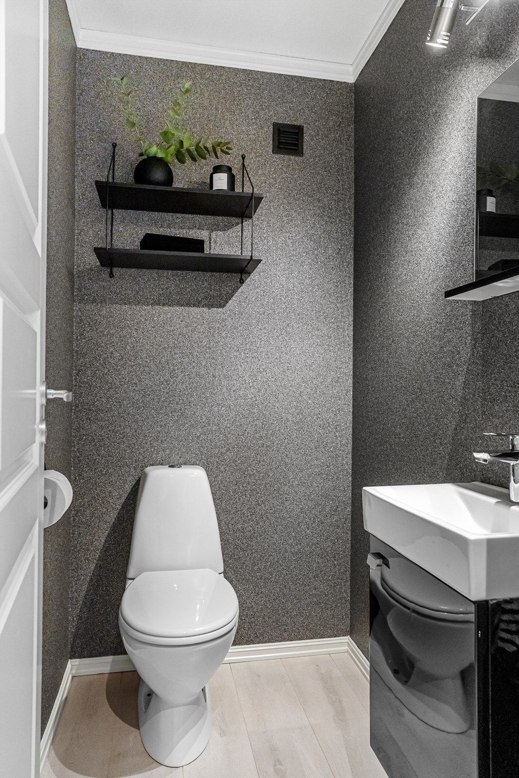 Pent toalettrom med laminat på gulvet og dekorativ tapet på veggene Galleribilde