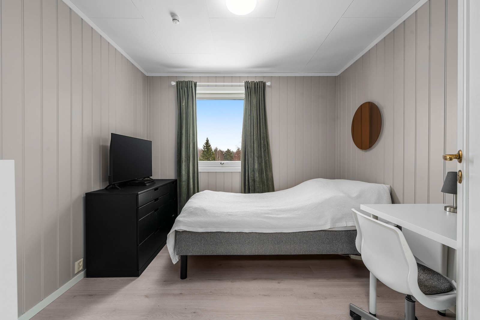 Boligens andre soverom i første etasje, med panel på veggene og laminat på gulvet. Galleribilde