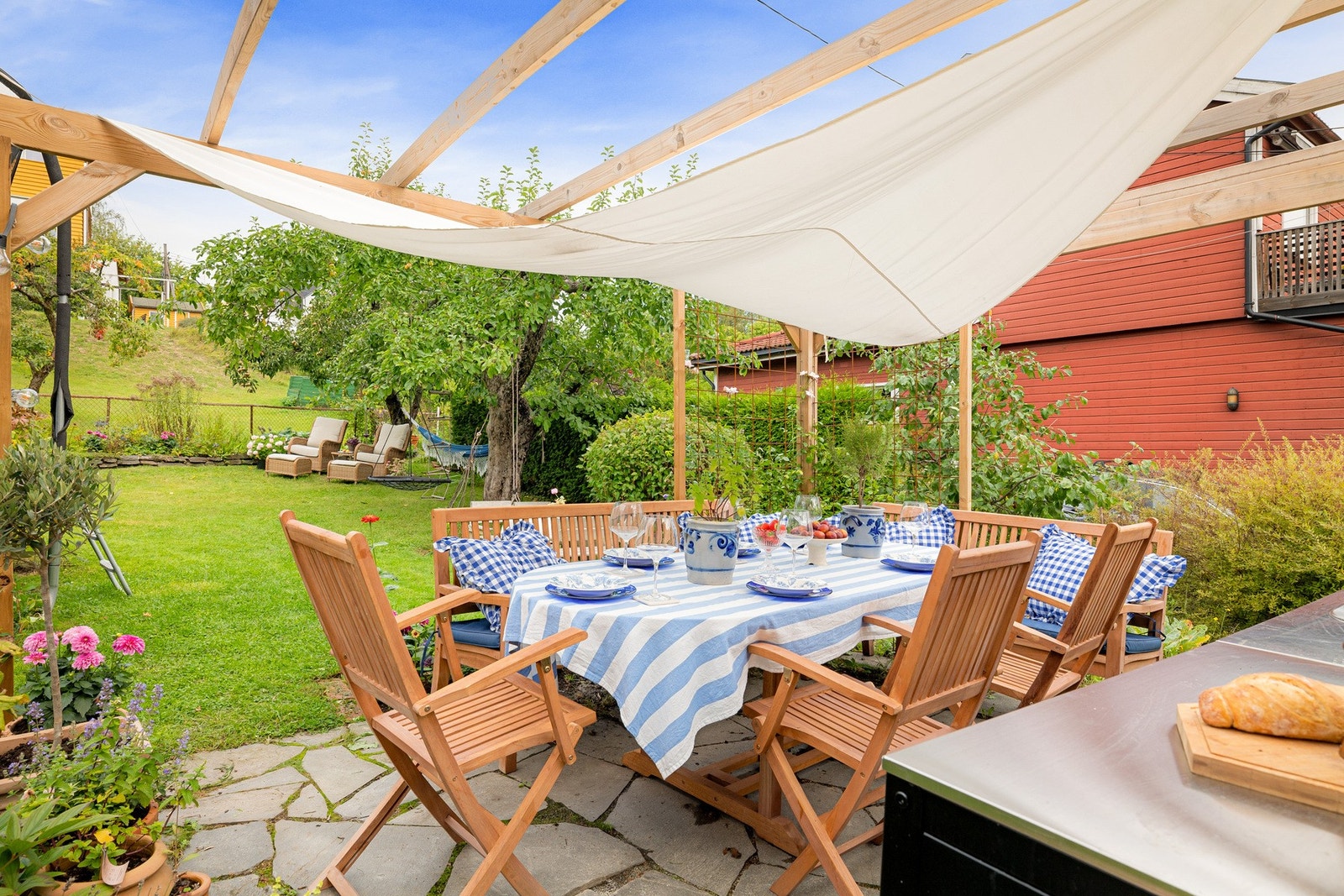 Den skiferbelagte sonen innbyr til hageselskap og sene sommerkvelder. Pergolaen er vakkert omkranset av blomsterbed med stauder og klatrevekster. Galleribilde