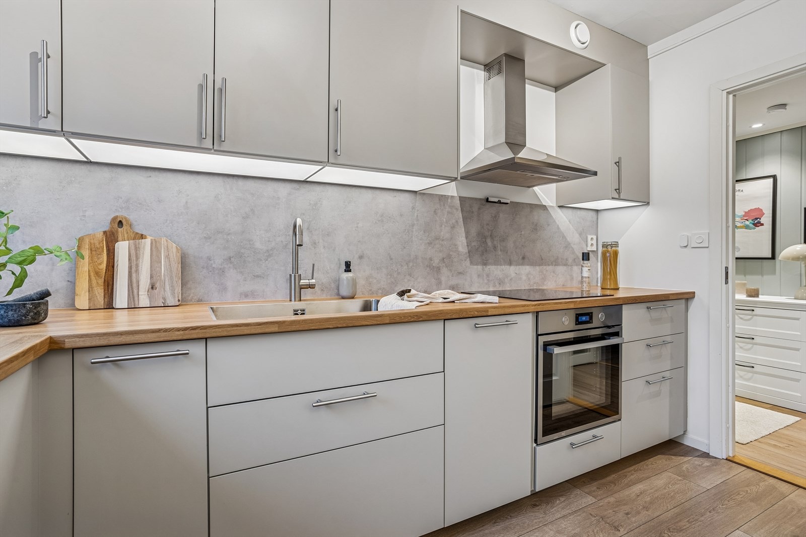 Kjøkkenet har en benkeplate i finérplate og praktisk belysning under overskapene. Galleribilde