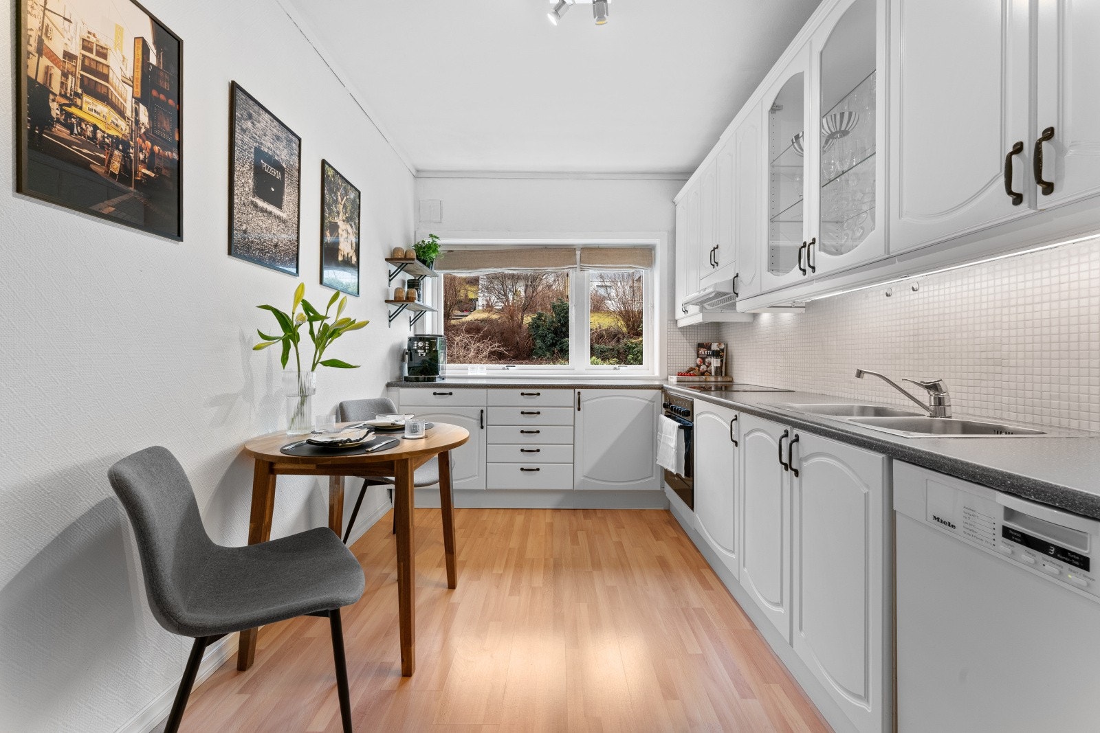 Innredning består av profilerte fronter og laminert benkeplate med kjøkkenvask. Integrerte hvitevarer er platetopp og stekeovn, mens kjøleskap og oppvaskmaskin er frittstående. Galleribilde