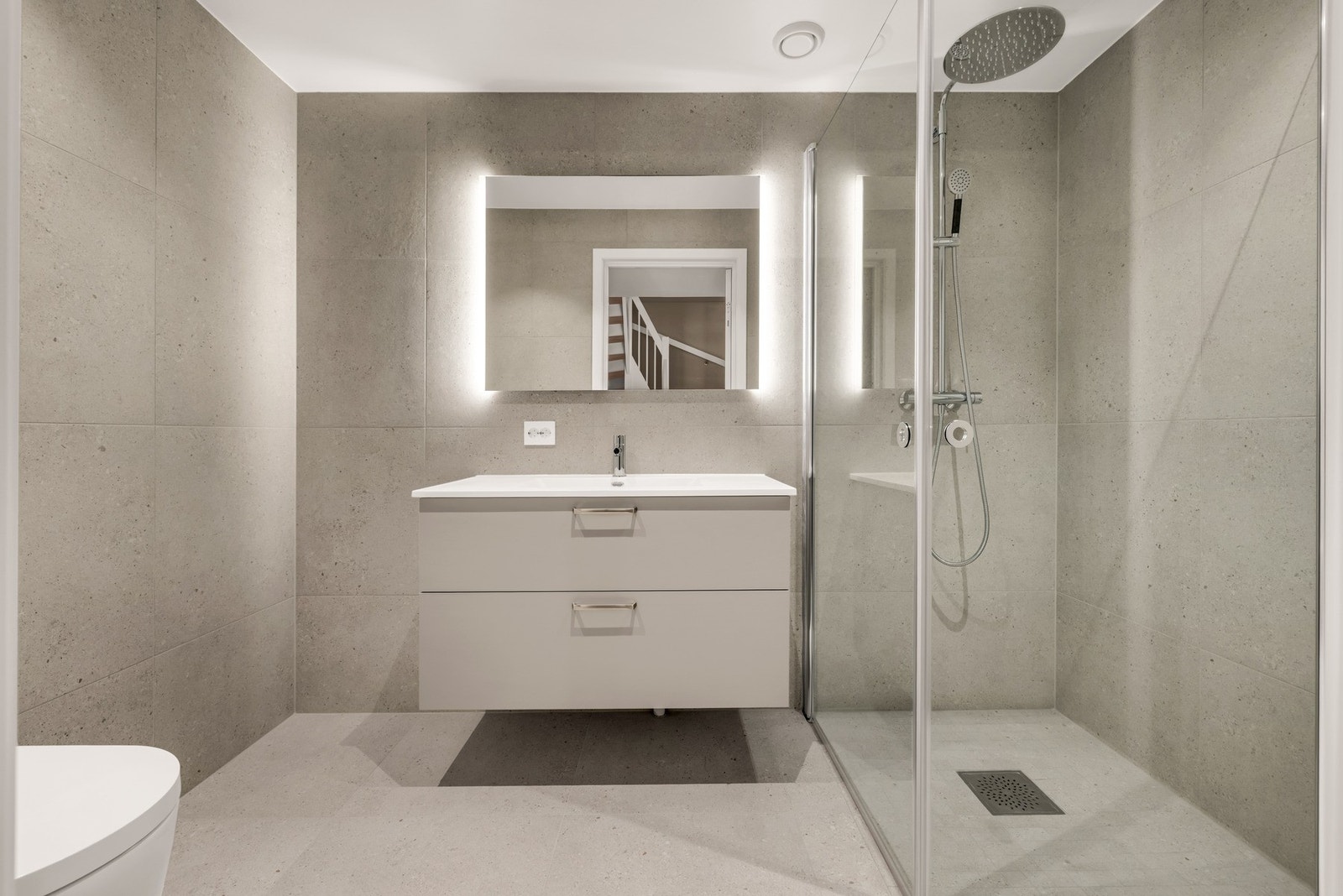 Bad/wc i u.etg med dusjnisje, servant med speil og veggmontert toalett. Galleribilde