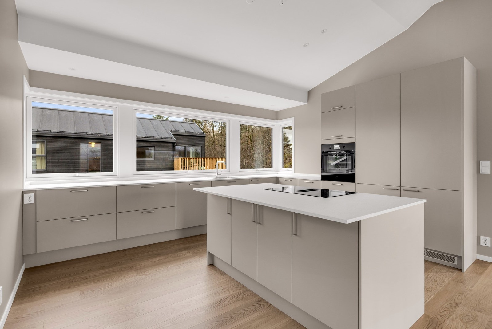 Stor kjøkken med integrerte hvitevarer som oppvaskmaskin, kjøl og fryseskap, integrert komfyr og platetopp med vifte. Galleribilde