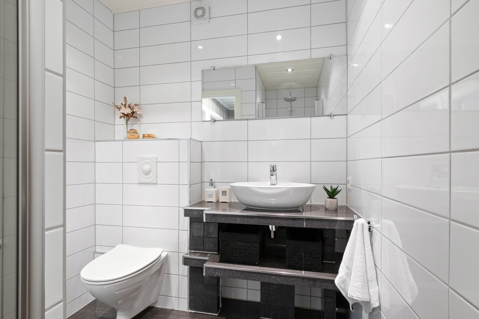 Badet har hvite fliser på veggene og koksgrå fliser på gulvet med gulvvarme. Galleribilde